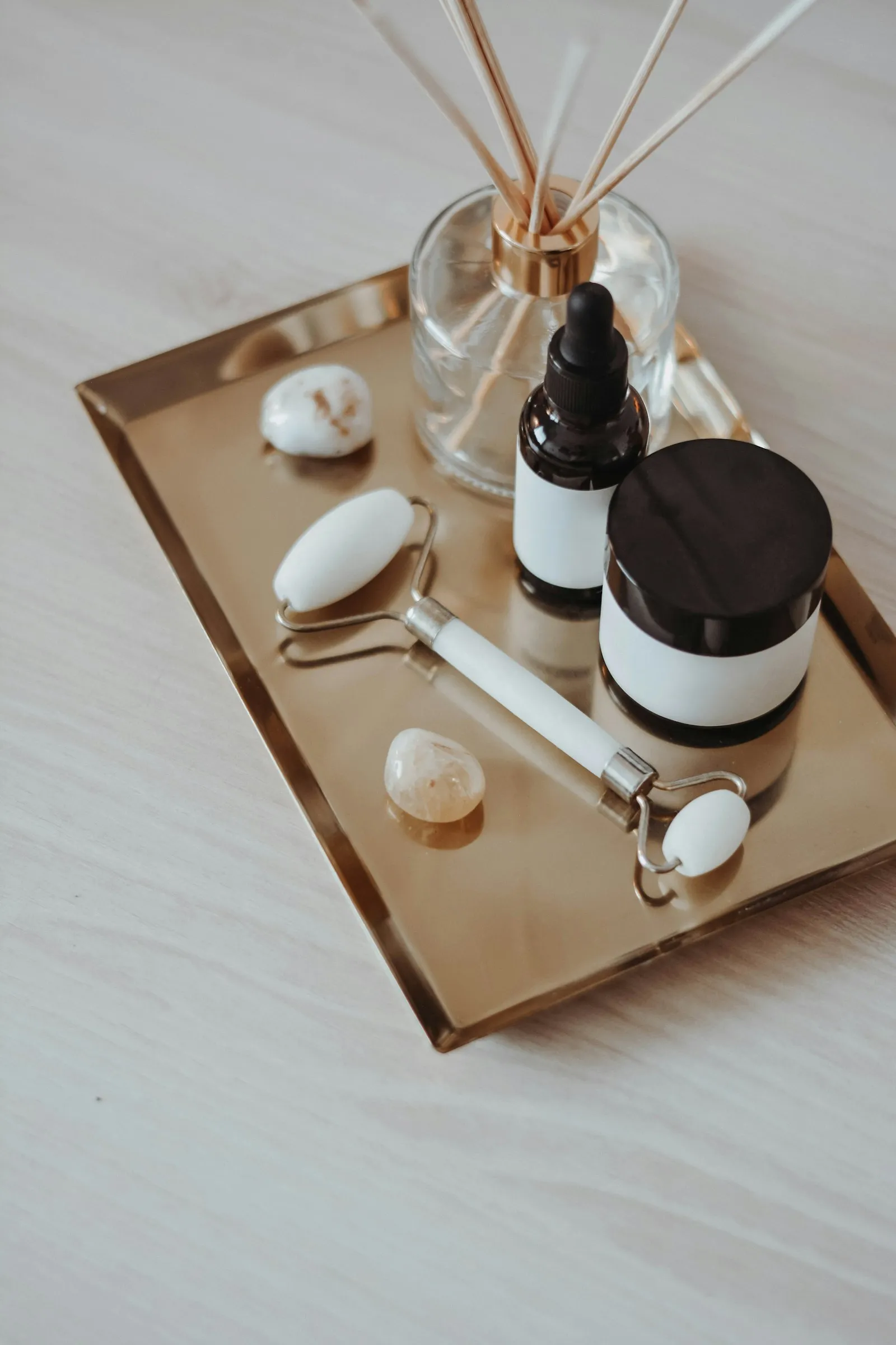 A facial roller and skincare jars on a gold tray